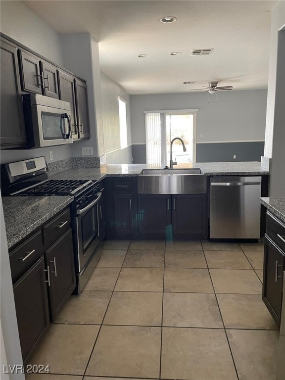 kitchen featuring stainless steel appliances, sink, light stone counters, and light tile patterned floors