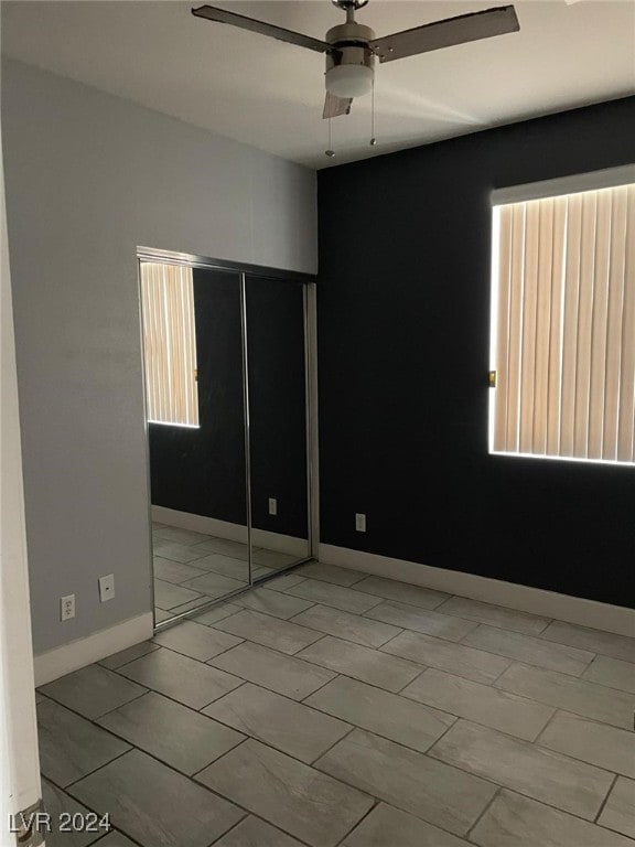 unfurnished bedroom featuring ceiling fan and a closet