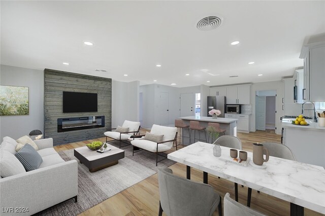 living room featuring a large fireplace, light hardwood / wood-style floors, and sink