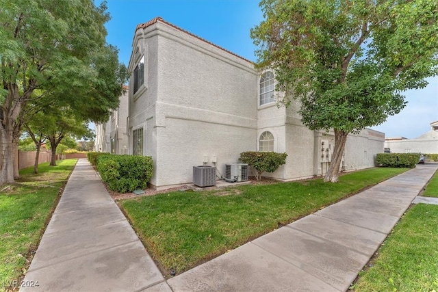 view of side of home featuring central AC unit and a yard