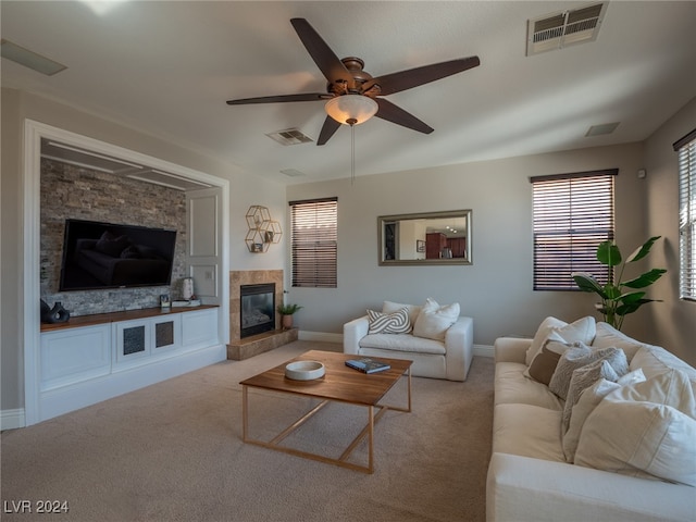 living room with ceiling fan, light colored carpet, and a fireplace