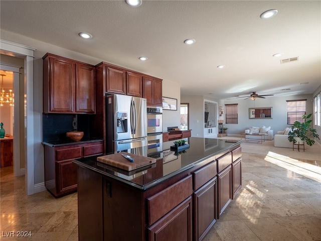 kitchen with ceiling fan with notable chandelier, stainless steel appliances, a center island, and a healthy amount of sunlight