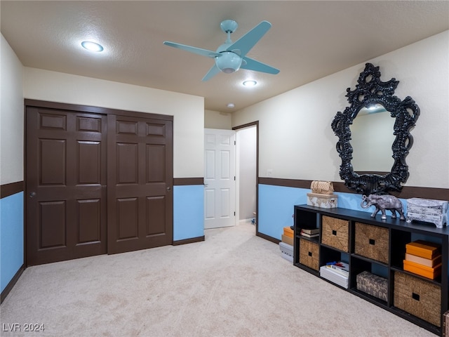 interior space featuring light colored carpet, a closet, and ceiling fan