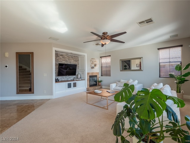 living room featuring ceiling fan, a fireplace, and light carpet