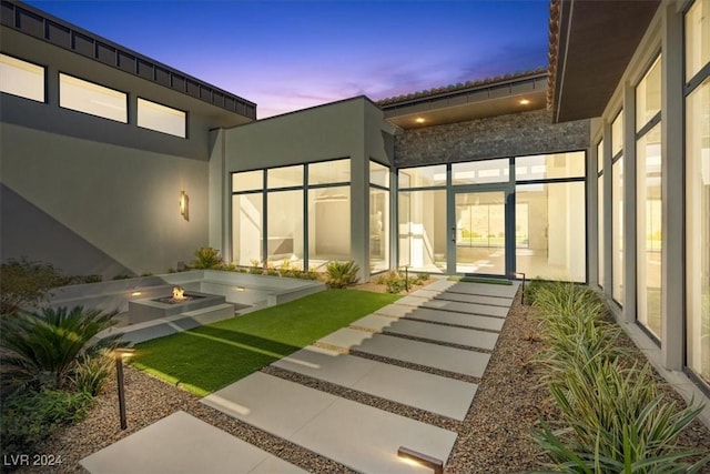 exterior space with stucco siding and an outdoor fire pit