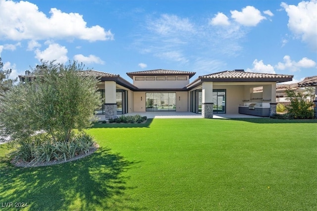 rear view of house with an outdoor kitchen, a patio area, and a yard