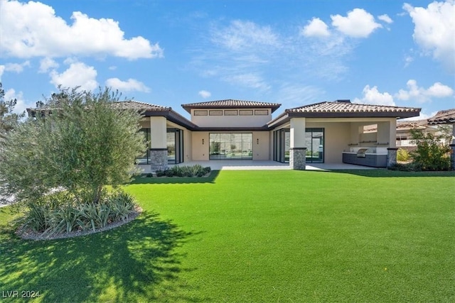 back of house with stucco siding, a patio, and a lawn