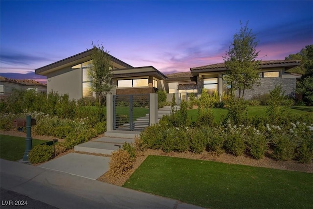 view of front of house featuring a yard, stucco siding, and a gate