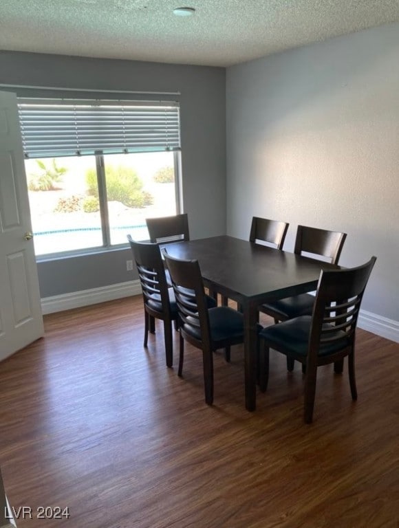 dining room featuring a healthy amount of sunlight, a textured ceiling, and hardwood / wood-style flooring