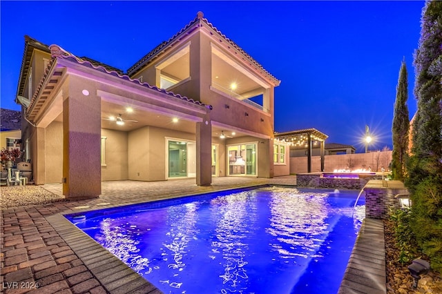 pool at twilight featuring an in ground hot tub, a patio, and pool water feature