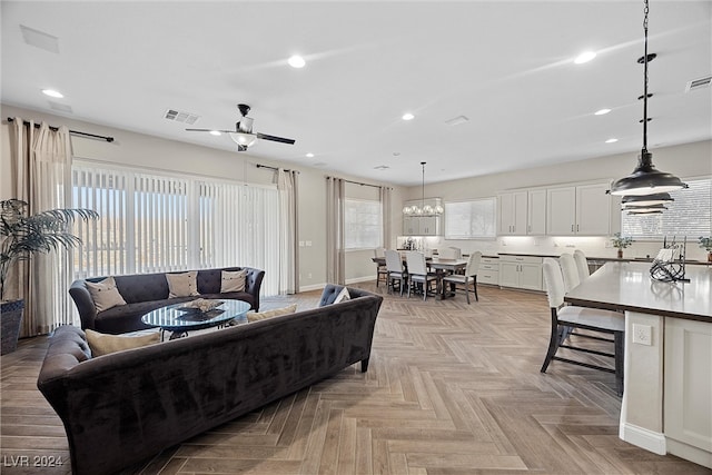 living room with ceiling fan with notable chandelier and light parquet floors