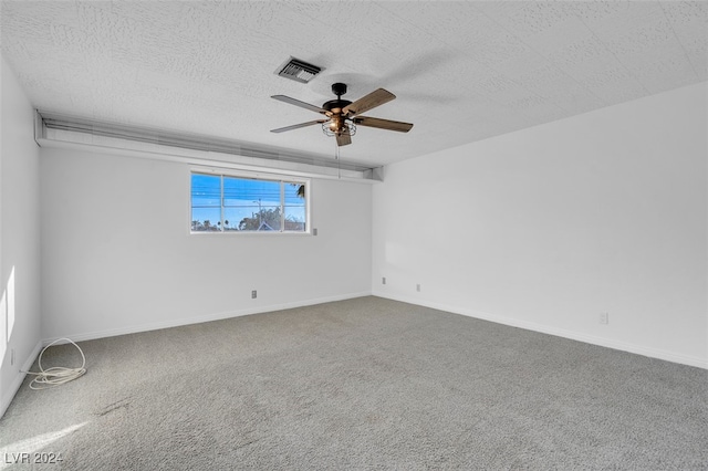 carpeted empty room featuring ceiling fan and a textured ceiling