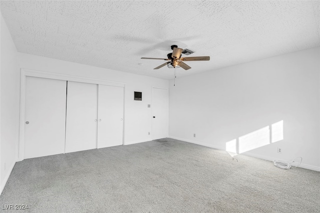 unfurnished bedroom with a textured ceiling, carpet flooring, and ceiling fan