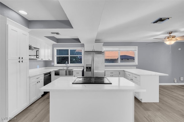 kitchen with appliances with stainless steel finishes, white cabinets, sink, and a kitchen island