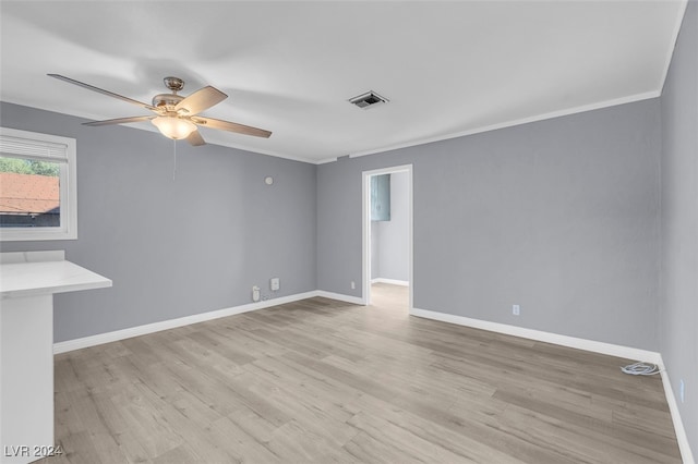 empty room featuring ceiling fan, light wood-type flooring, and ornamental molding