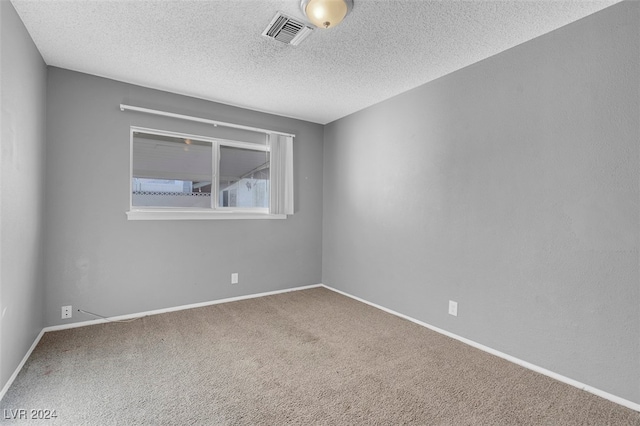 carpeted empty room featuring a textured ceiling