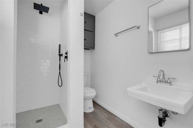 bathroom featuring sink, wood-type flooring, toilet, and tiled shower