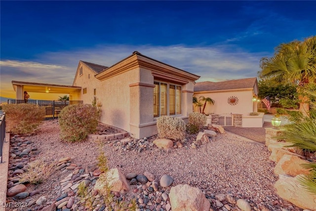 property exterior at dusk featuring fence and stucco siding