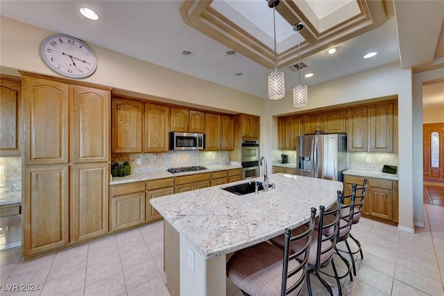 kitchen with stainless steel appliances, visible vents, hanging light fixtures, a sink, and an island with sink