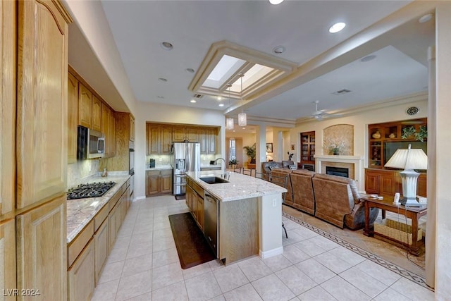 kitchen with open floor plan, hanging light fixtures, a kitchen island with sink, stainless steel appliances, and a sink