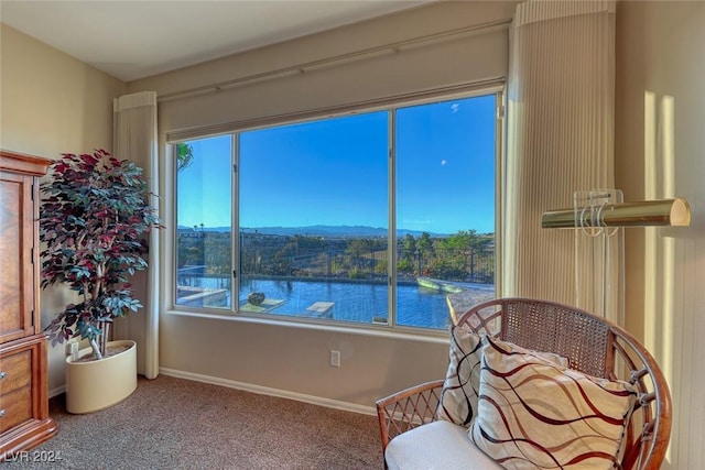 sitting room with plenty of natural light, a water view, and carpet