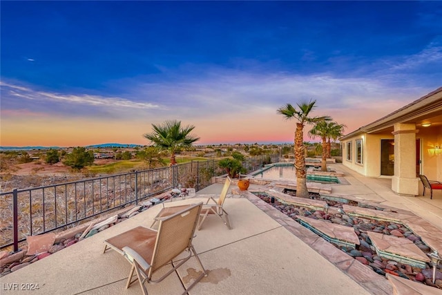 patio terrace at dusk featuring a fenced in pool and a fenced backyard