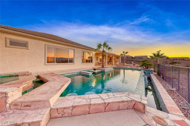 view of swimming pool with a patio area, a pool with connected hot tub, and fence