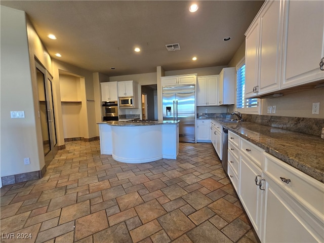 kitchen with white cabinets, sink, a center island, and built in appliances