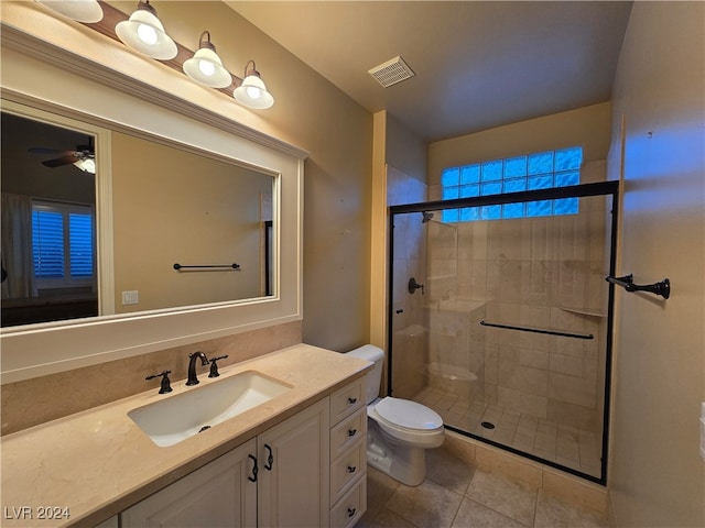 bathroom with tile patterned floors, a shower with door, vanity, toilet, and ceiling fan