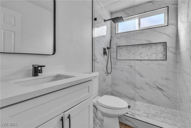 bathroom featuring vanity, toilet, and tiled shower