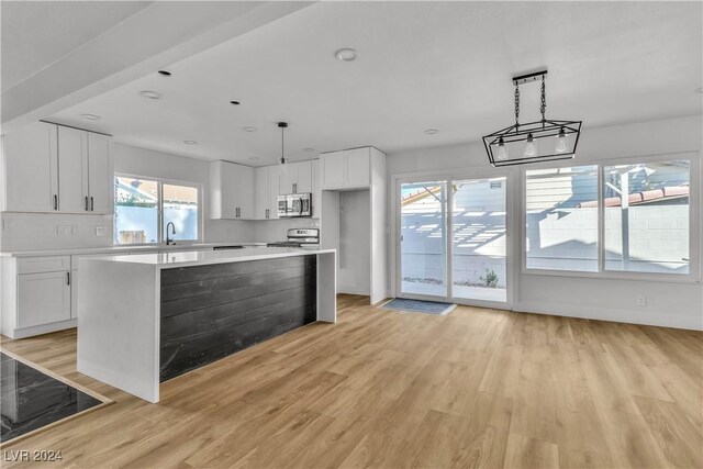 kitchen with white cabinets, a kitchen island, light hardwood / wood-style floors, and appliances with stainless steel finishes