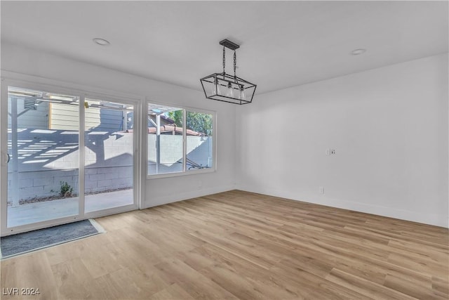 unfurnished dining area featuring light wood-type flooring and a notable chandelier