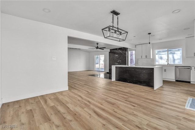 kitchen featuring white cabinets, decorative light fixtures, stainless steel dishwasher, and a wealth of natural light