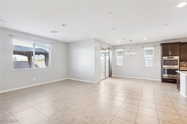 unfurnished living room with light tile patterned flooring and an inviting chandelier