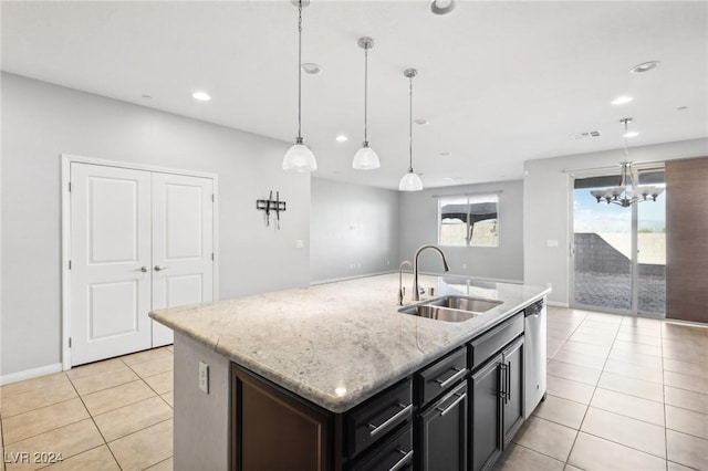 kitchen with sink, hanging light fixtures, stainless steel dishwasher, light stone countertops, and an island with sink