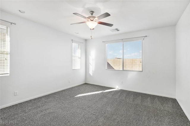 spare room featuring dark carpet and ceiling fan