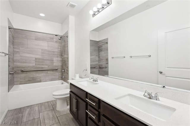 full bathroom featuring tiled shower / bath combo, toilet, and vanity