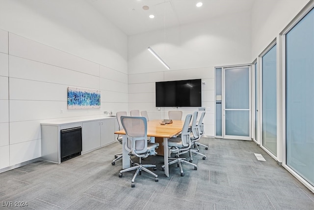 dining area featuring light colored carpet and a high ceiling