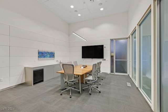 home office featuring a towering ceiling and light colored carpet