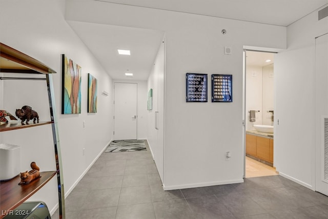 hall featuring sink and light tile patterned floors