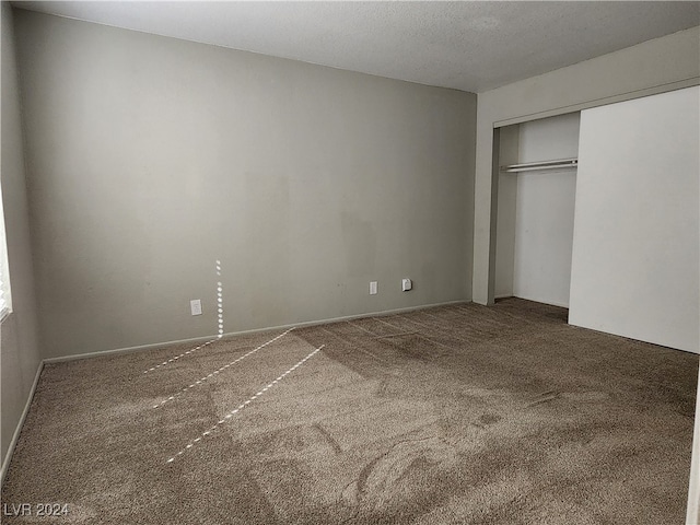 unfurnished bedroom featuring a textured ceiling, a closet, and carpet