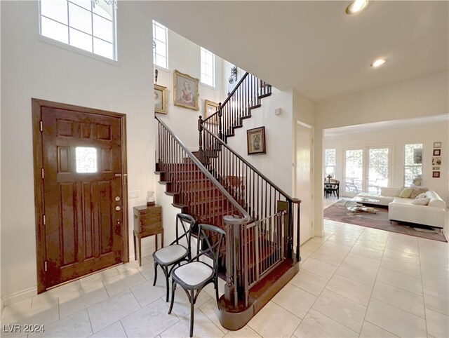 entrance foyer with light tile patterned floors and a towering ceiling