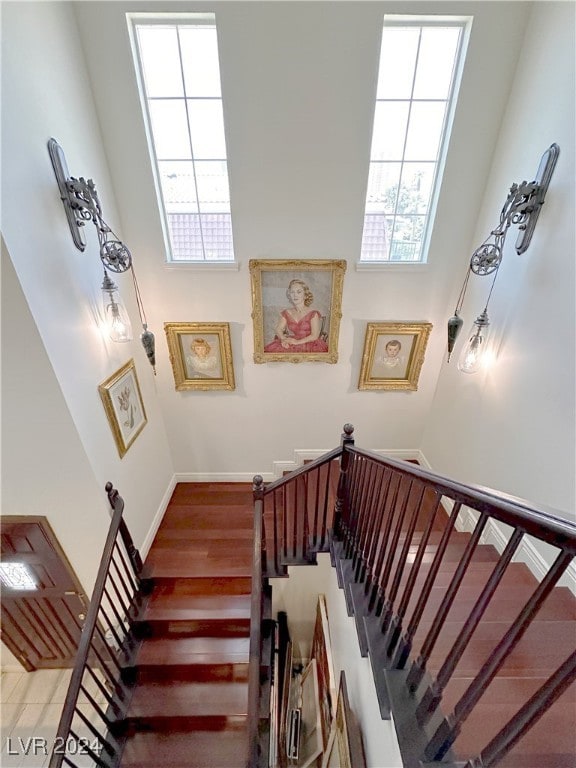 stairs featuring a towering ceiling and wood-type flooring