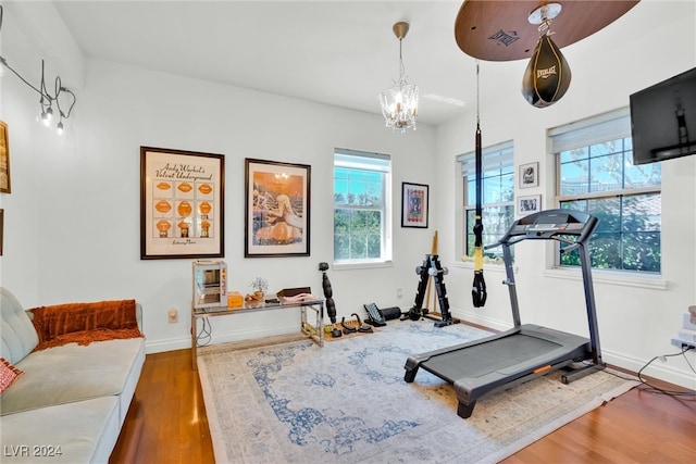 workout area with an inviting chandelier, a wealth of natural light, and hardwood / wood-style floors