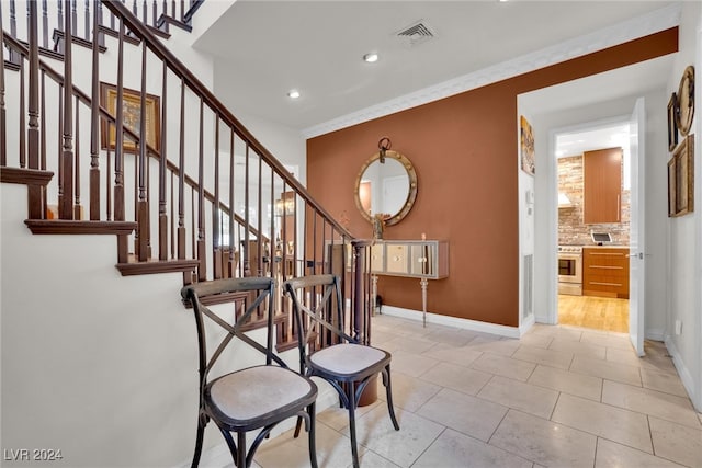 stairs with tile patterned flooring and crown molding