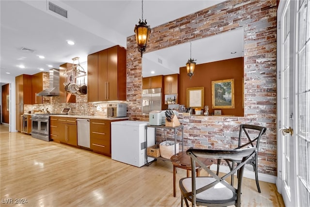 kitchen with stainless steel appliances, tasteful backsplash, light wood-type flooring, wall chimney range hood, and pendant lighting