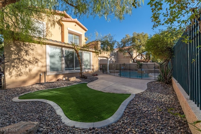 rear view of property with a fenced in pool, a yard, and a patio area