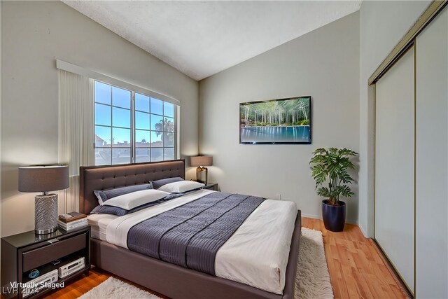 bedroom with a closet, light wood-type flooring, and lofted ceiling