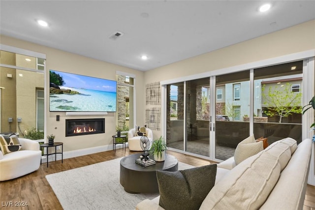 living area with recessed lighting, baseboards, wood finished floors, and a glass covered fireplace