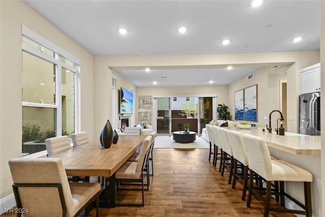 dining area with a lit fireplace, visible vents, wood finished floors, and recessed lighting